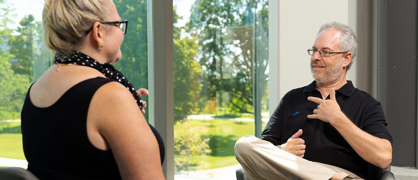 A man and a woman speaking to each other using American Sign Language.